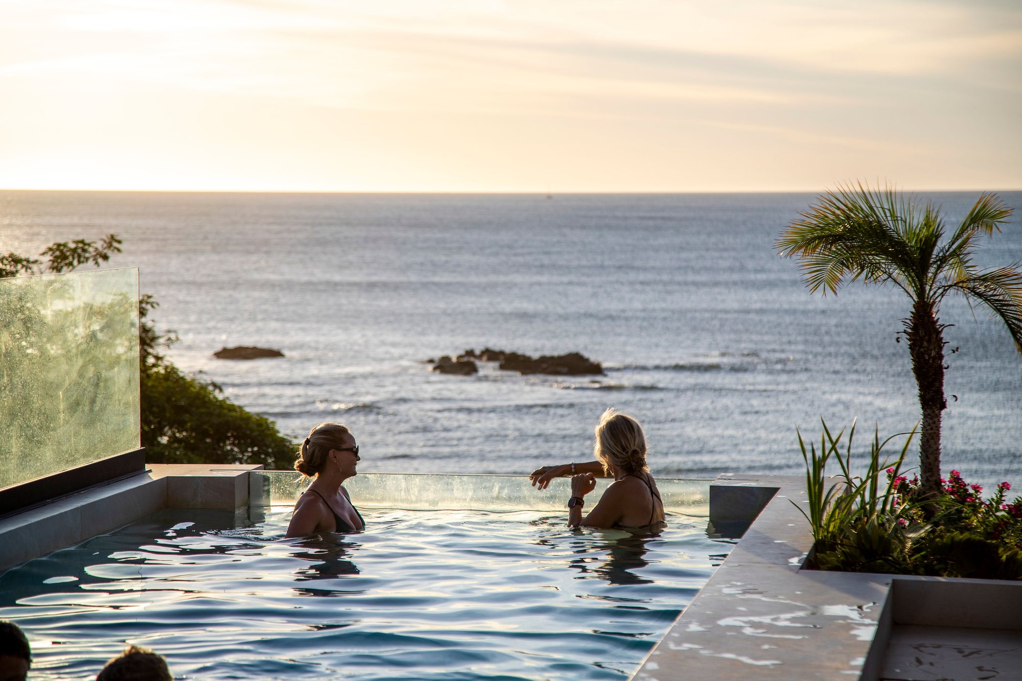Guests in the rooftop pool as dusk settles over Tamarindo