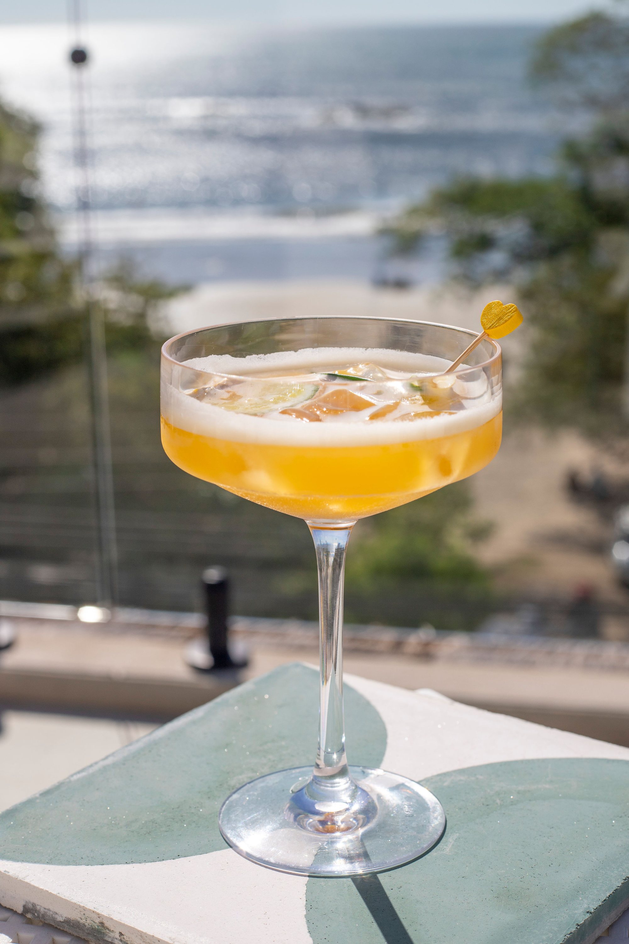 A handcrafted cocktail on the rooftop with the Pacific in the background